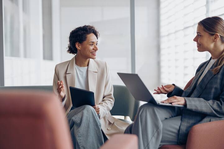 Stylish female coworkers talking during business meeting in cozy office. Teamwork concept