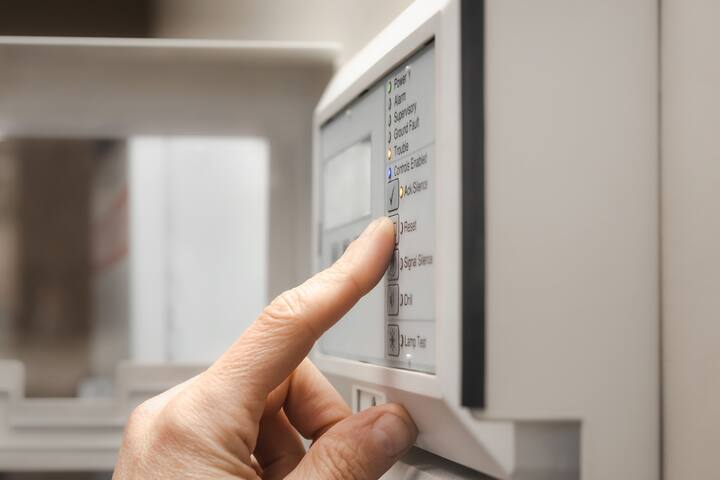 Fire alarm technician using the fire alarm control panel or annunciator. Finger is on reset button on the control panel in service room or lobby of residential or commercial building. Selective focus.