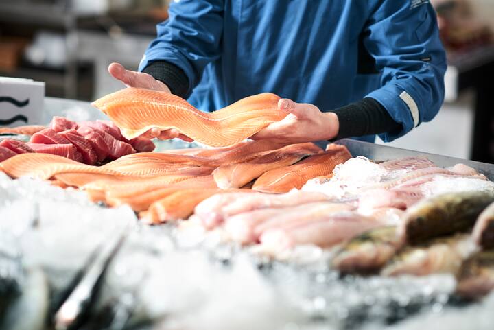 A young male shop assistant in a fishshop saling fresh fish