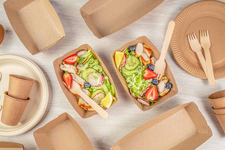salad with chicken and vegetables served in recyclable containers. Eco friendly disposable dishes.