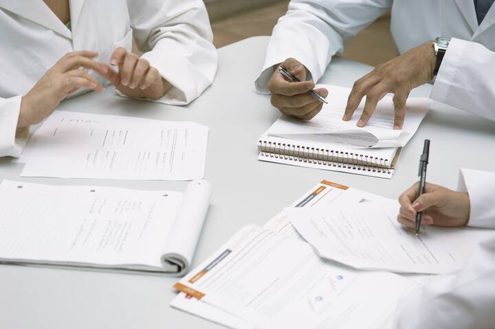 Colleagues doing paperwork together --- Image by © Fancy/Veer/Corbis