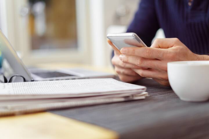 mann sitzt am tisch und schaut auf sein mobiltelefon