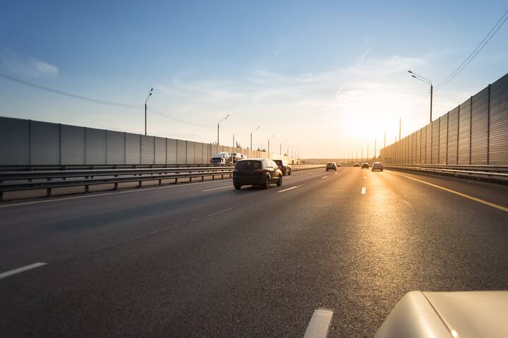 Highway noise barrier, Acoustic Screen. cars on the road in the evening sun.