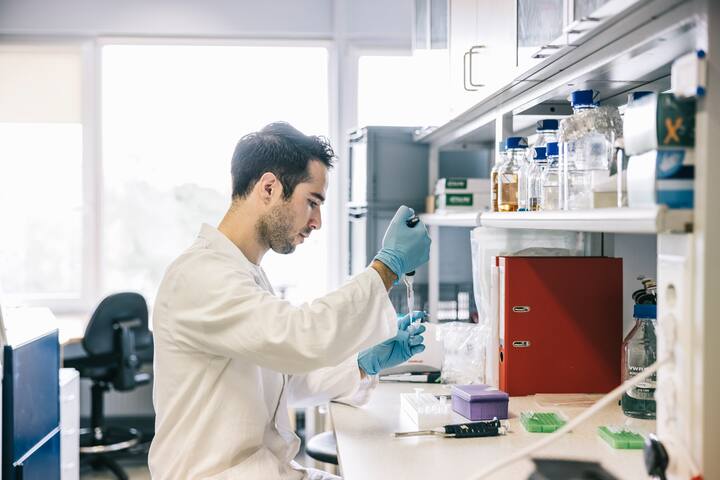 Concentrated scientist taking samples with pipette in laboratory.