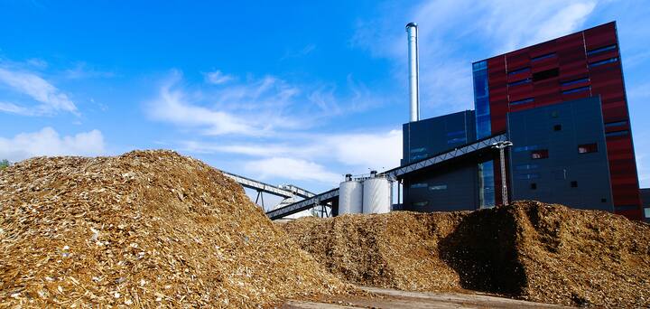 bio power plant with storage of wooden fuel (biomass) against blue sky