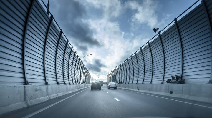 Cars on the sound-absorbing tunnel at the asphalt road. Metal structure with plastic parts. Modern technology in the Moscow Russia
