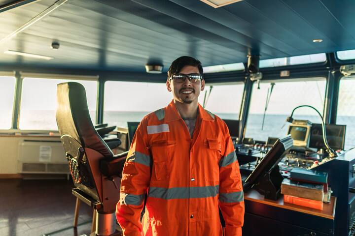 Filipino deck Officer on bridge of vessel or ship wearing coverall during navigaton watch at sea.