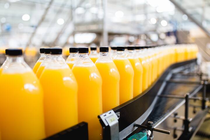 Bottling factory - Orange juice bottling line for processing and bottling juice into bottles. Selective focus.