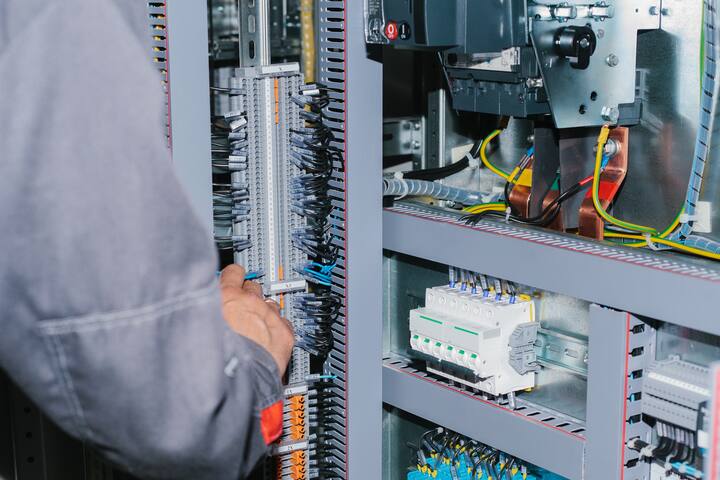 Photo of male electrical technician specialist checking indoor electric low-voltage cabinet equipment