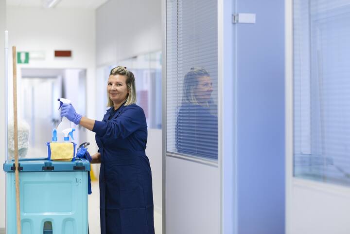Women at work, portrait of happy professional female cleaner smiling and looking at camera in office. Three quarter length