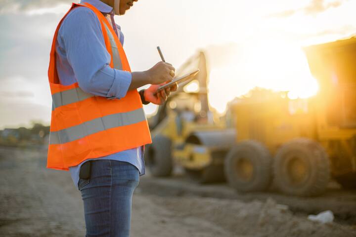 Asian engineer with hardhat using tablet pc computer inspecting and working at construction site