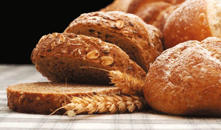 Sliced integral bread, wheat, and various baking on checked table cloth 