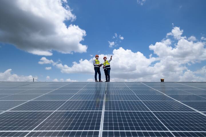 Engineers walking on roof inspect and check solar cell panel by hold equipment box and radio communication ,solar cell is smart grid ecology energy sunlight alternative power factory concept